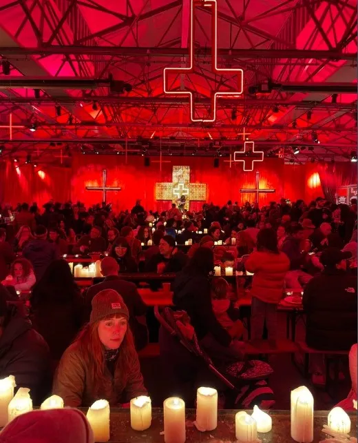 Candles and neon crosses in a red-lit hall at Dark Mofo