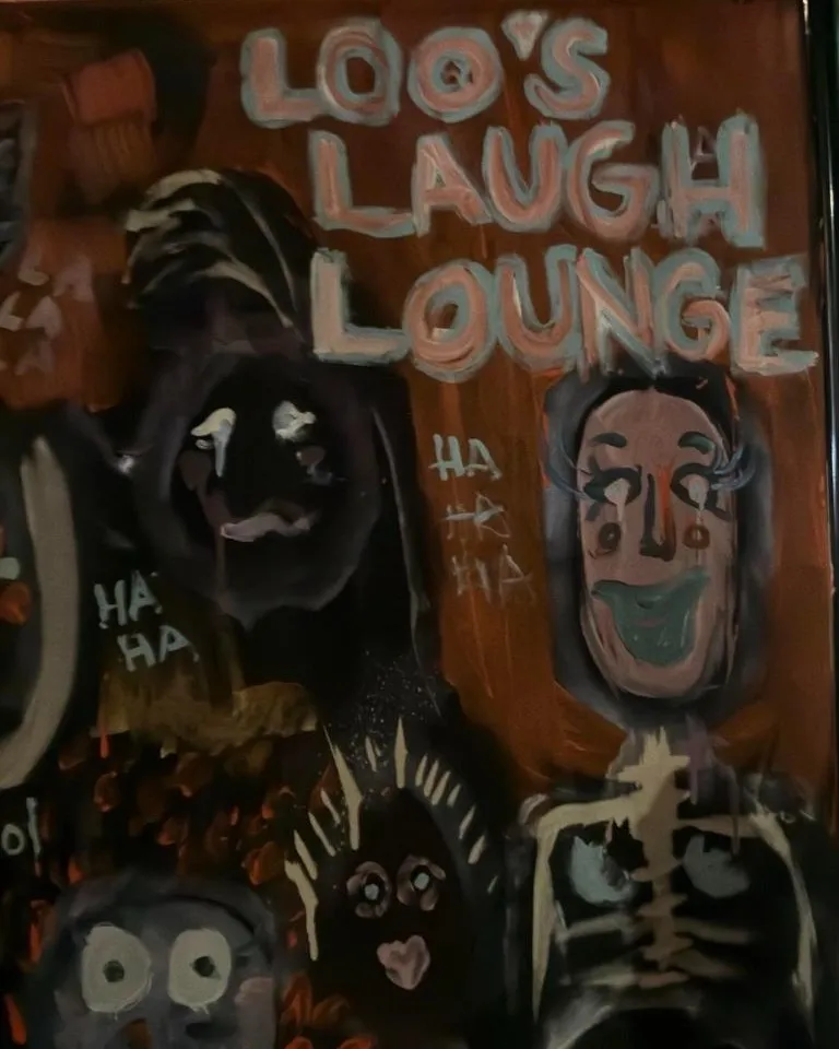 The Loo's Laugh Lounge painting, faces in dark paint on a rust-brown canvas