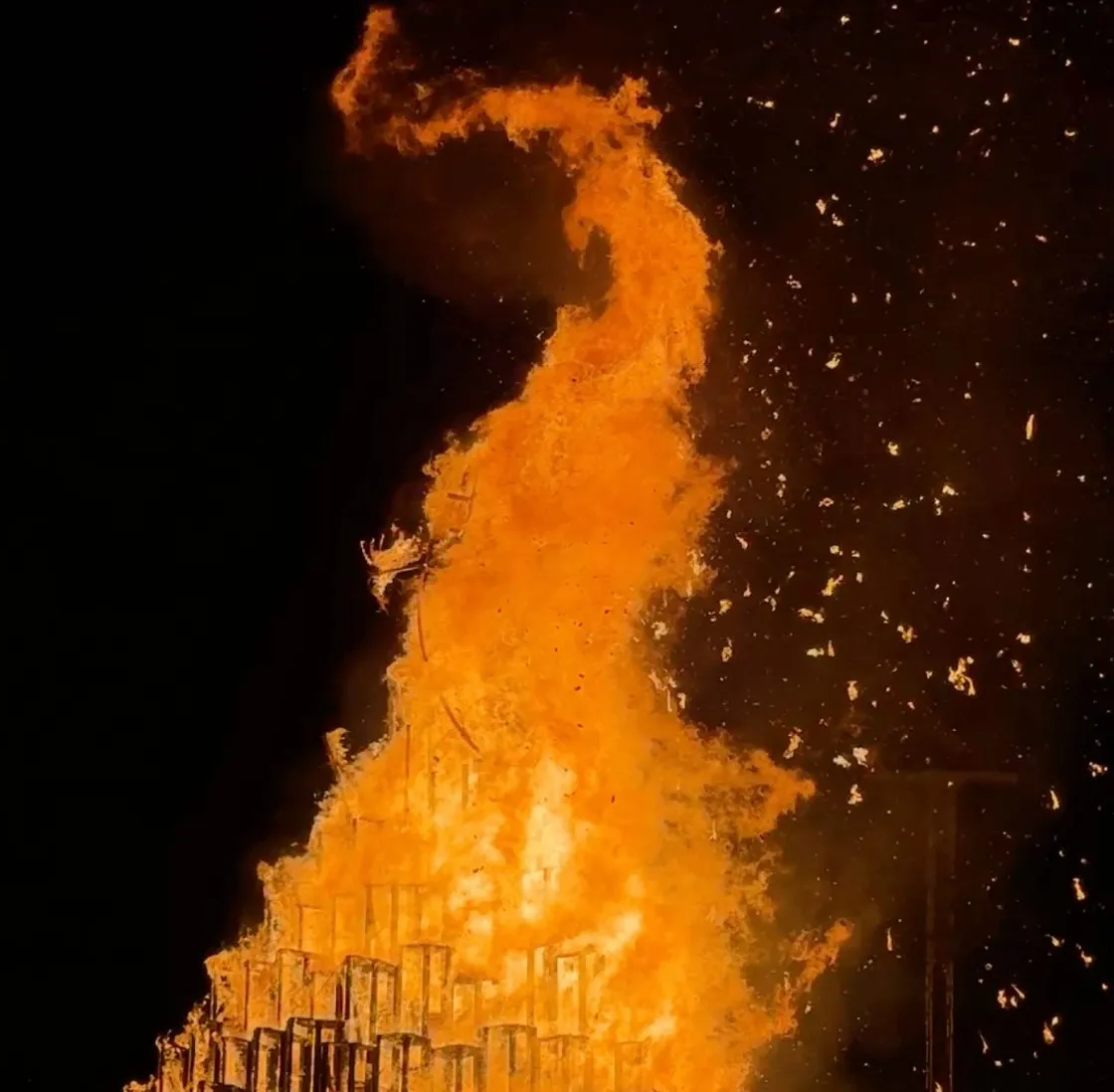 The pyre consumed by a towering column of orange flame and sparks