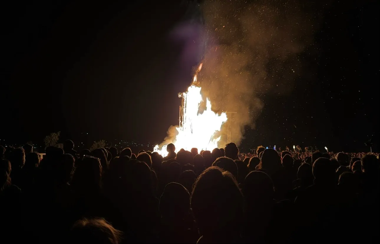 A crowd silhouetted against the Ogoh-Ogoh as it burns at night
