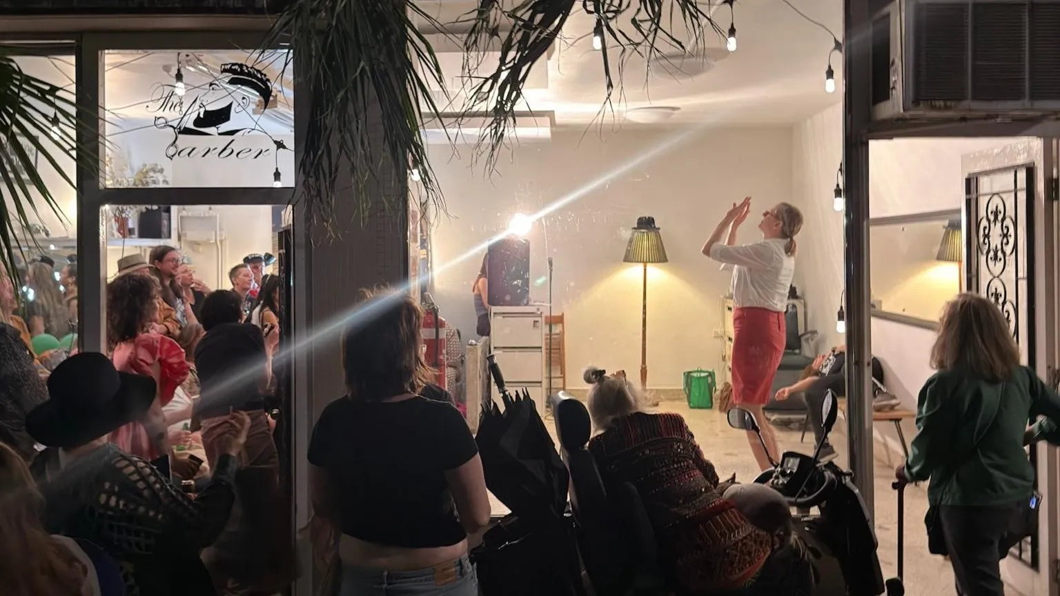 Loo’s Lounge on its opening night, the old barber shop lit up and the footpath crowded while a performer moves inside